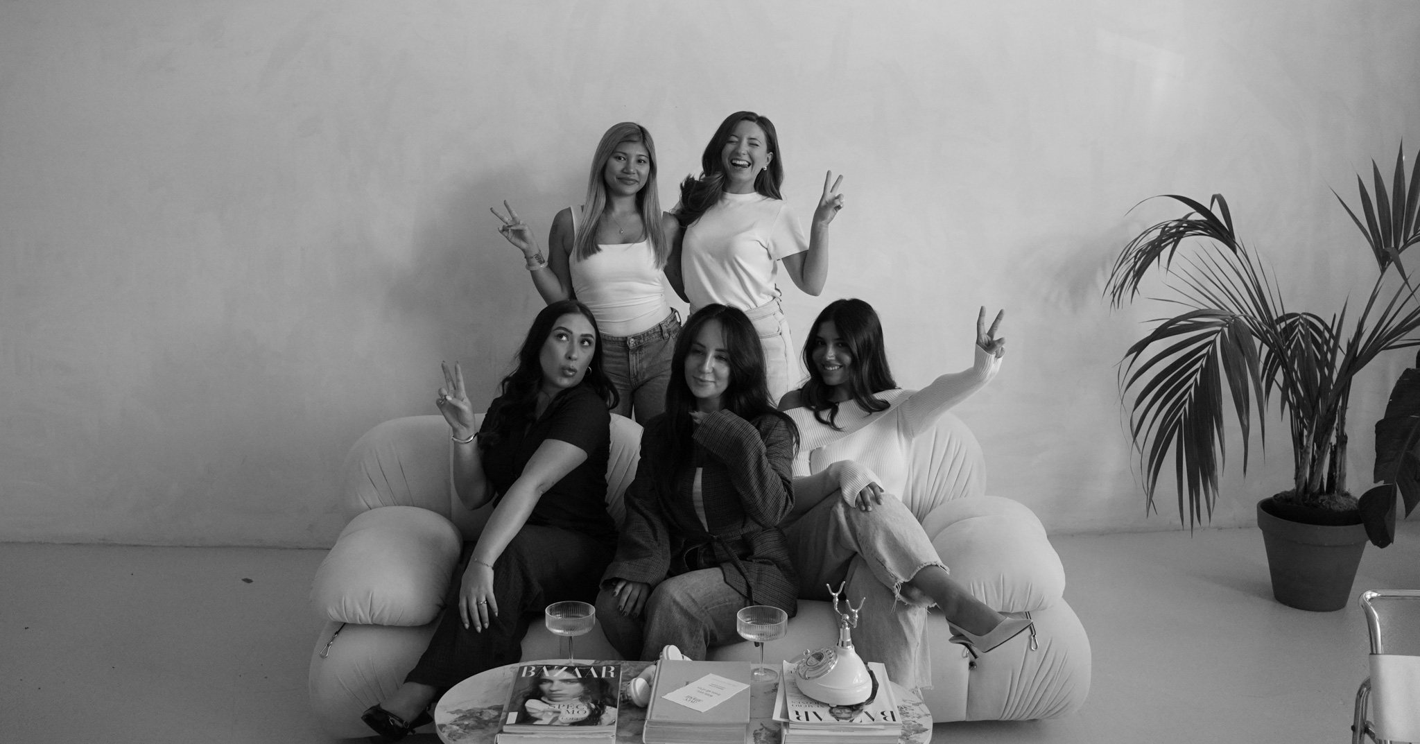 Melissa, Georgia, Nadiye, Michelle and Lauren on a sofa, laughing and making peace signs